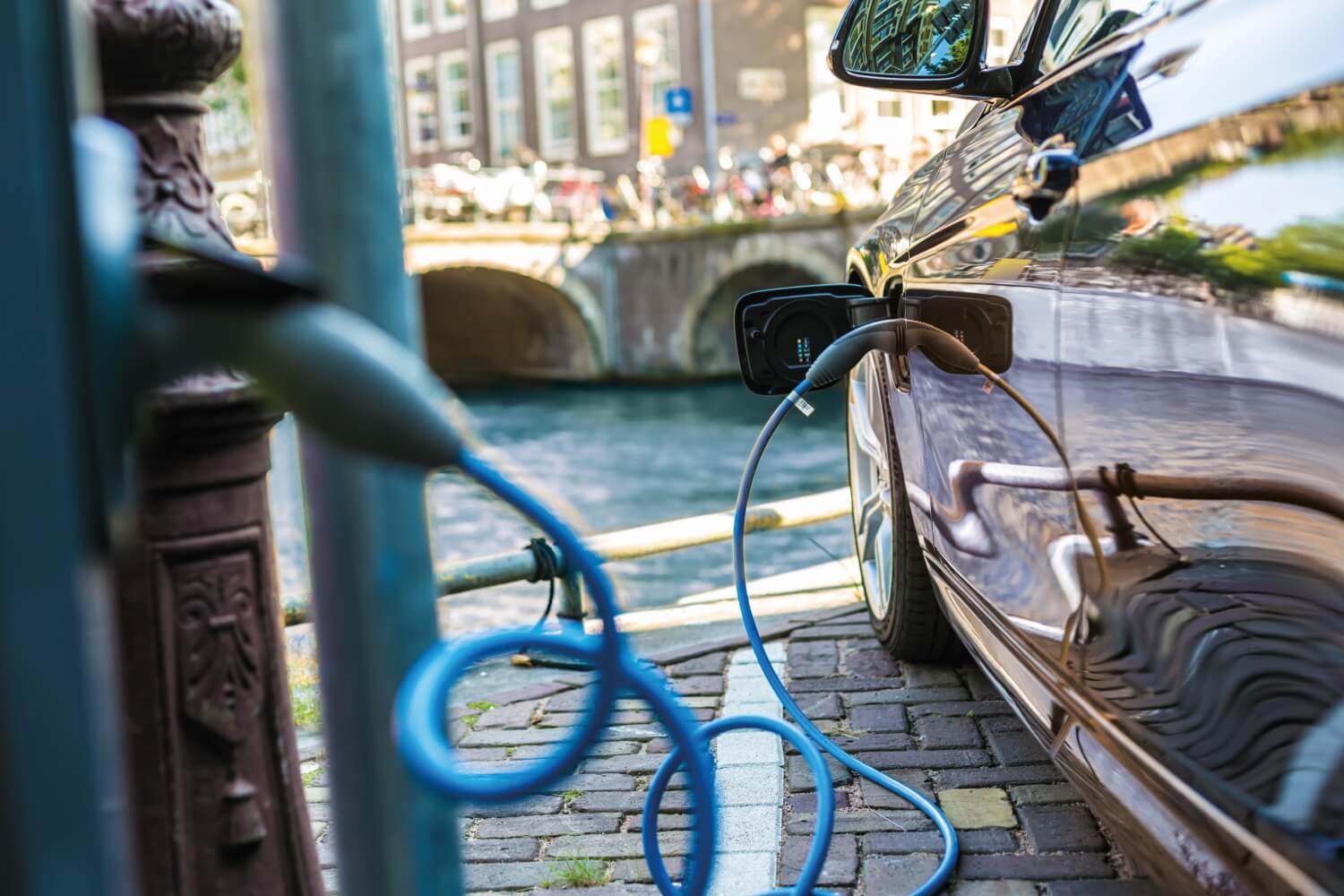 Ein Elektrofahrzeug wird in der Stadt nahe des Flussufers an einer Ladesäule geladen.