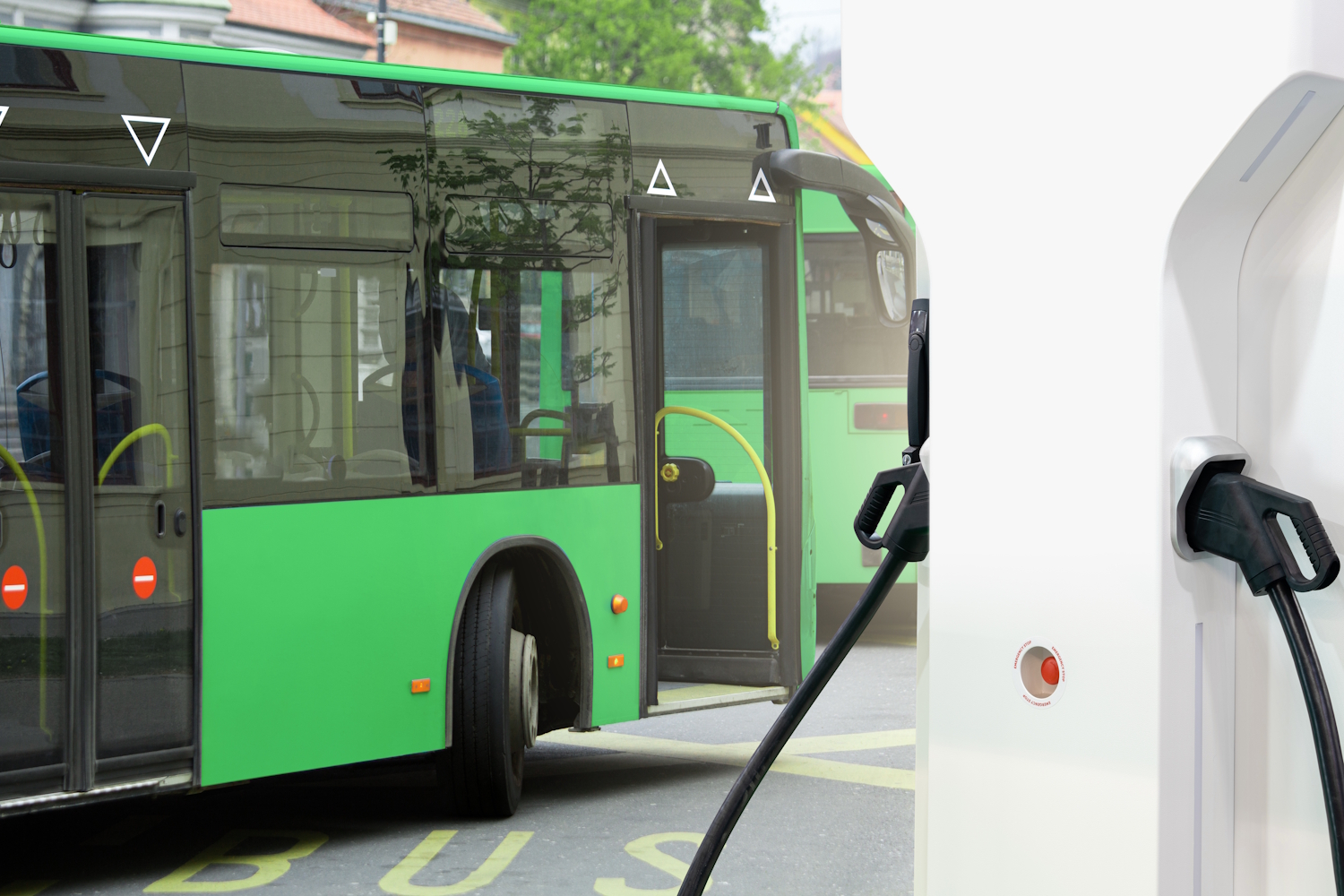 Grüner Elektrobus wird an einer Ladestation aufgeladen.