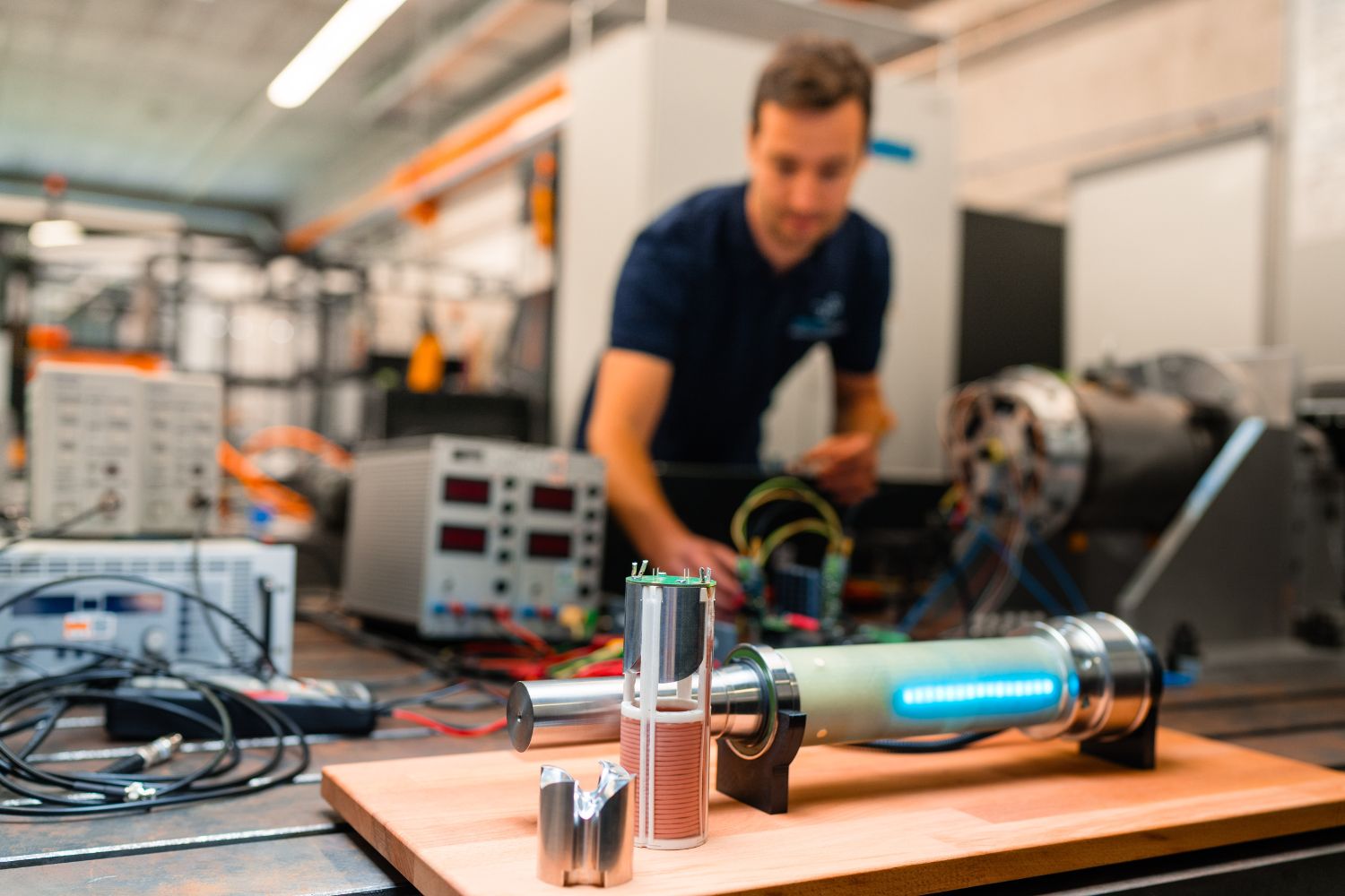 Ein Mann steht hinter einem Tisch mit verschiedenen elektrischen Geräten. Im Vordergrund ist ein Elektromotor des InnovationsCampus Mobilität der Zukunft (ICM) gut sichtbar platziert.