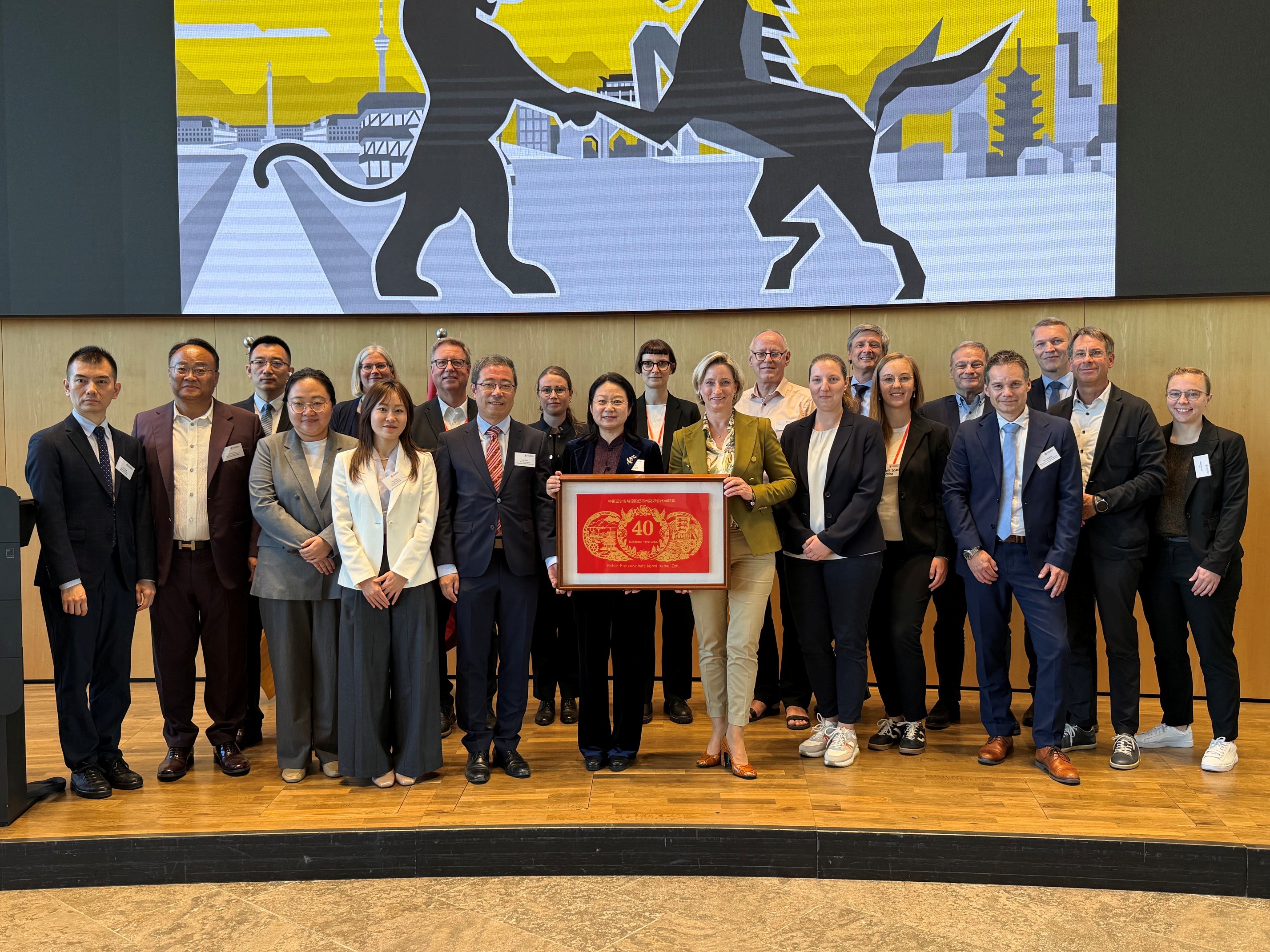 40 Jahre Partnerschaft: Baden-Württemberg und Liaoning Eine Gruppe chinesischer und deutscher Menschen, die lächelnd in die Kamera blicken. Sie stehen auf einer Bühne.