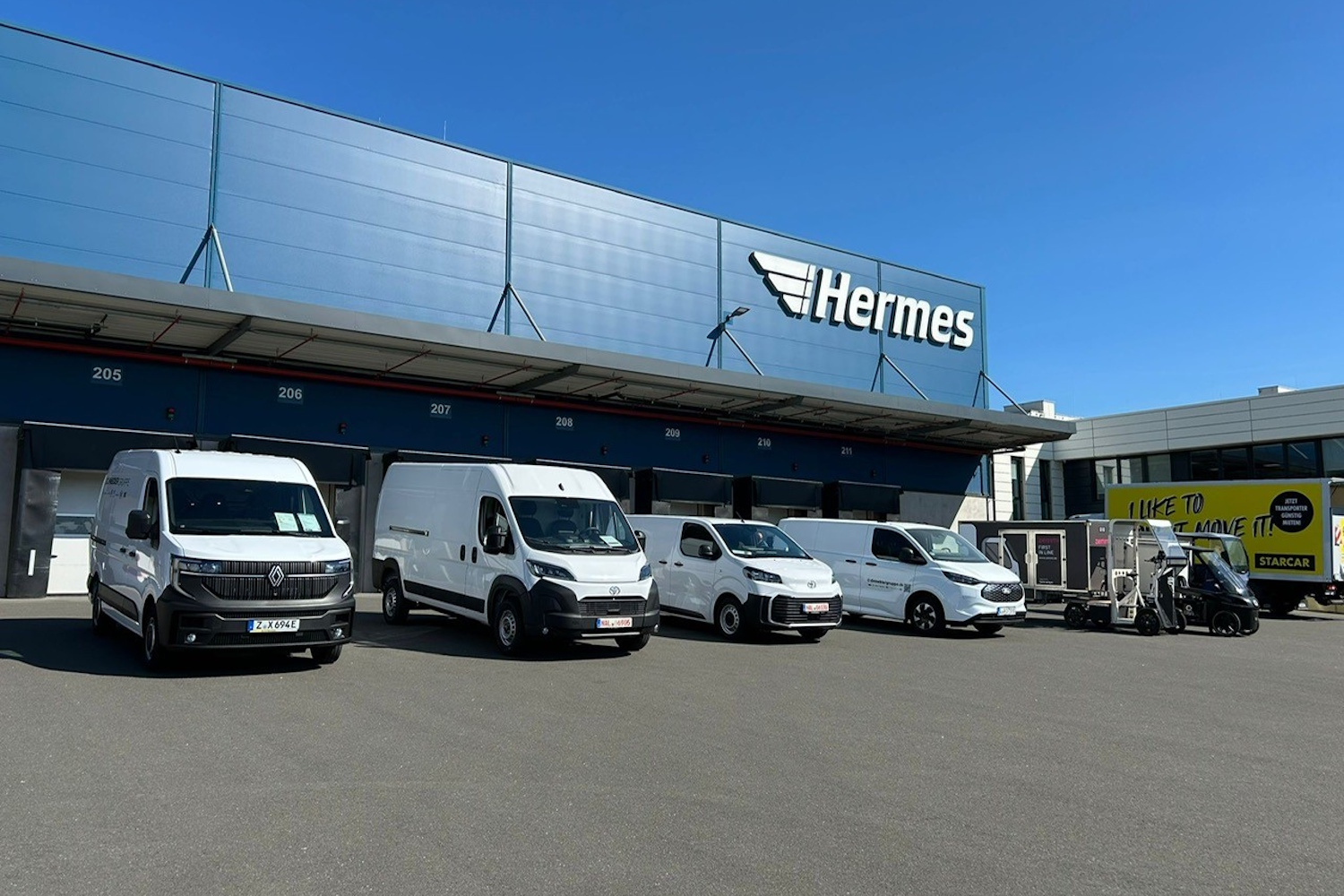 Das Bild zeigt verschiedene Nutzfahrzeuge parkend vor einem Hermes-Depot.