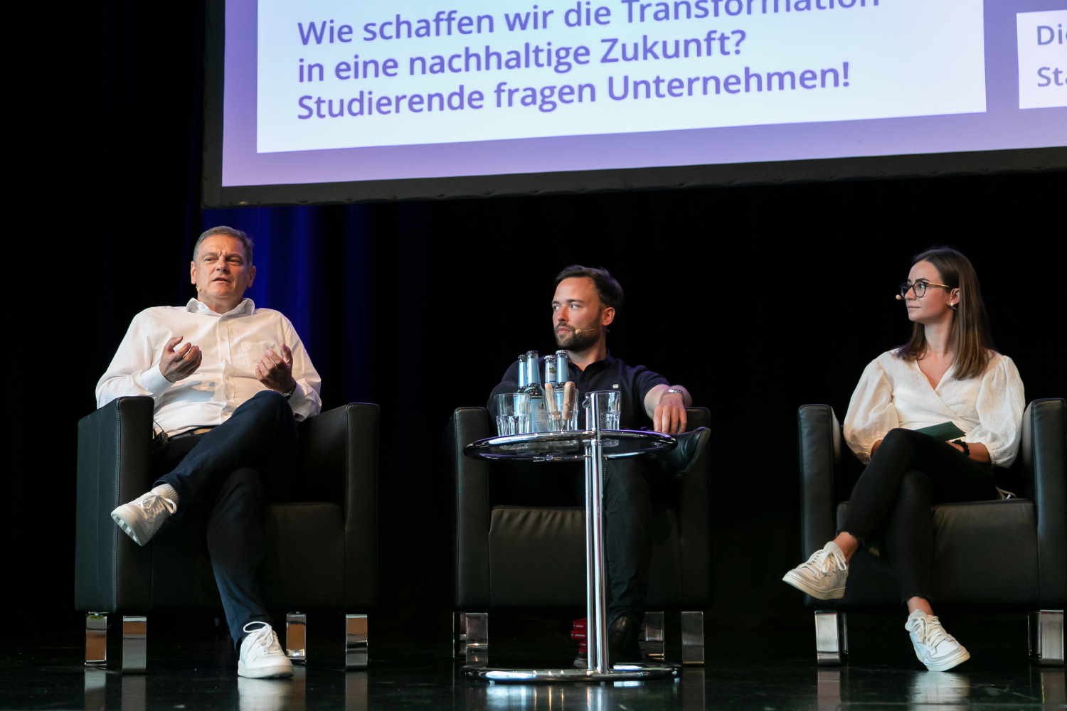 Drei Personen diskutieren gemeinsam auf einem Podium.